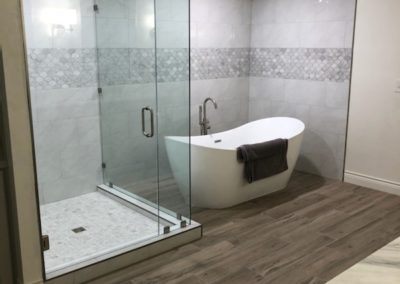 New bathroom with glass shower and a new white bathtub.